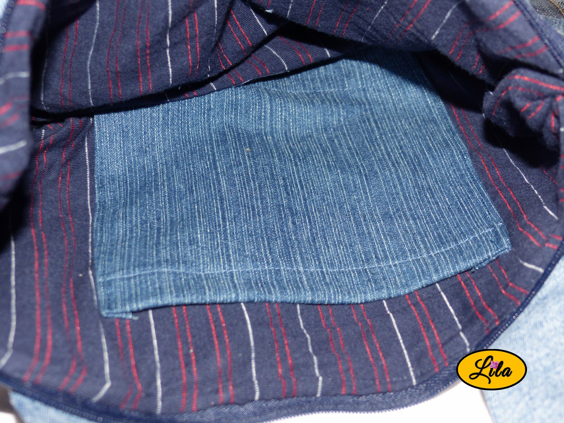 Zoom sur l’intérieur du sac à main multi-poches en jeans recyclé avec doublure bleu foncé rayée bleu et rouge et poche intérieure en jeans