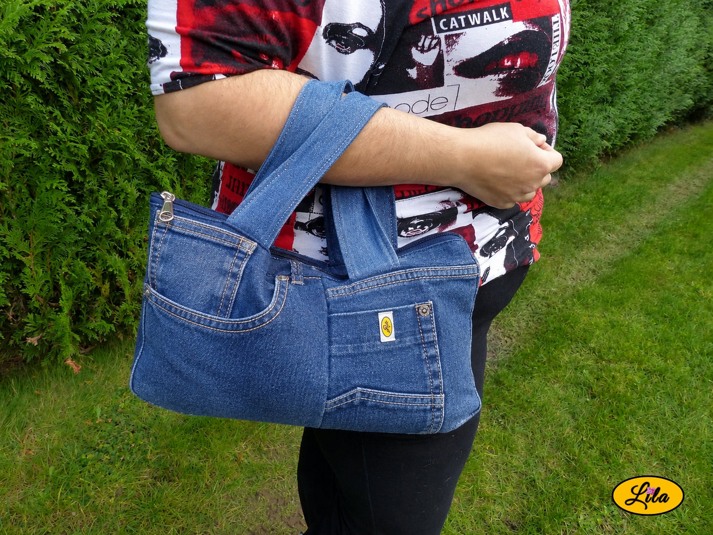 Sac à main multi-poches en jeans recyclé porté dans le creux du bras en extérieur photo cadrée sur le sac style urbain et artisanal