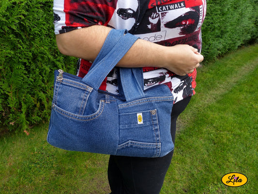 Sac à main multi-poches en jeans recyclé porté dans le creux du bras en extérieur photo cadrée sur le sac style urbain et artisanal