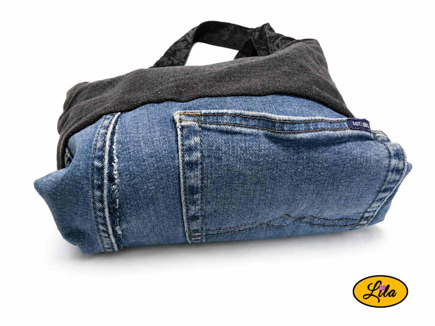 Fond d’un sac patchwork en jeans recyclés vu à plat sur fond blanc avec partie en jean bleu foncé et poche intégrée visible style upcycling et pratique