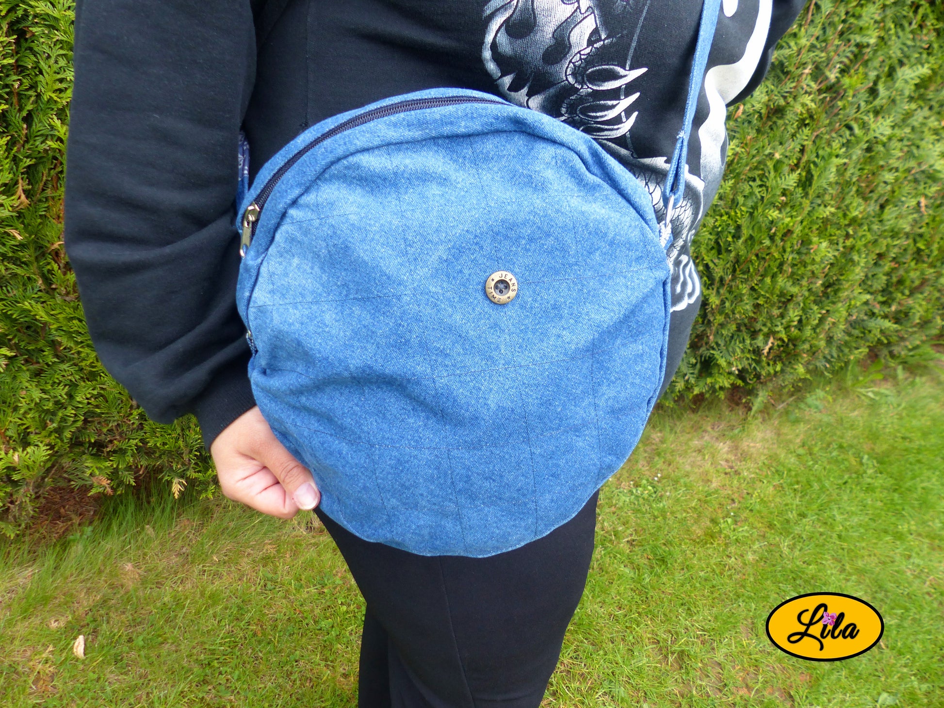 Sac rond en jeans porté en extérieur cadré sur la taille avec bouton d’origine du vêtement visible style urbain et artisanal