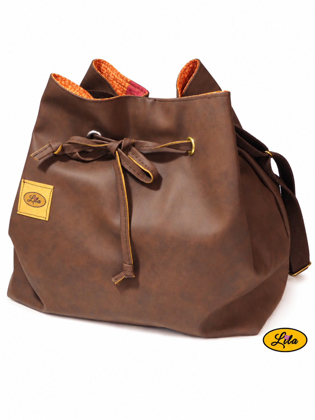 Sac seau en simili cuir brun foncé vu de face sur fond blanc avec sangle bandoulière brune derrière et lien coulissant formant un nœud, création artisanale upcyclée