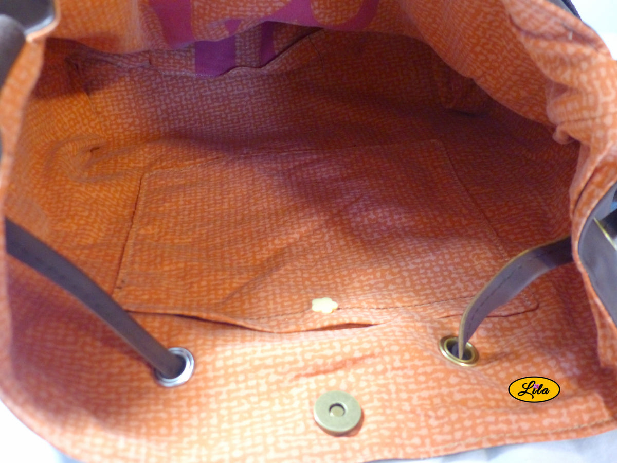 Vue de l'intérieur d'un sac seau en simili cuir brun foncé avec doublure en tissu orangé recyclé et poche intérieure fermée par une attache pression, création artisanale upcyclée