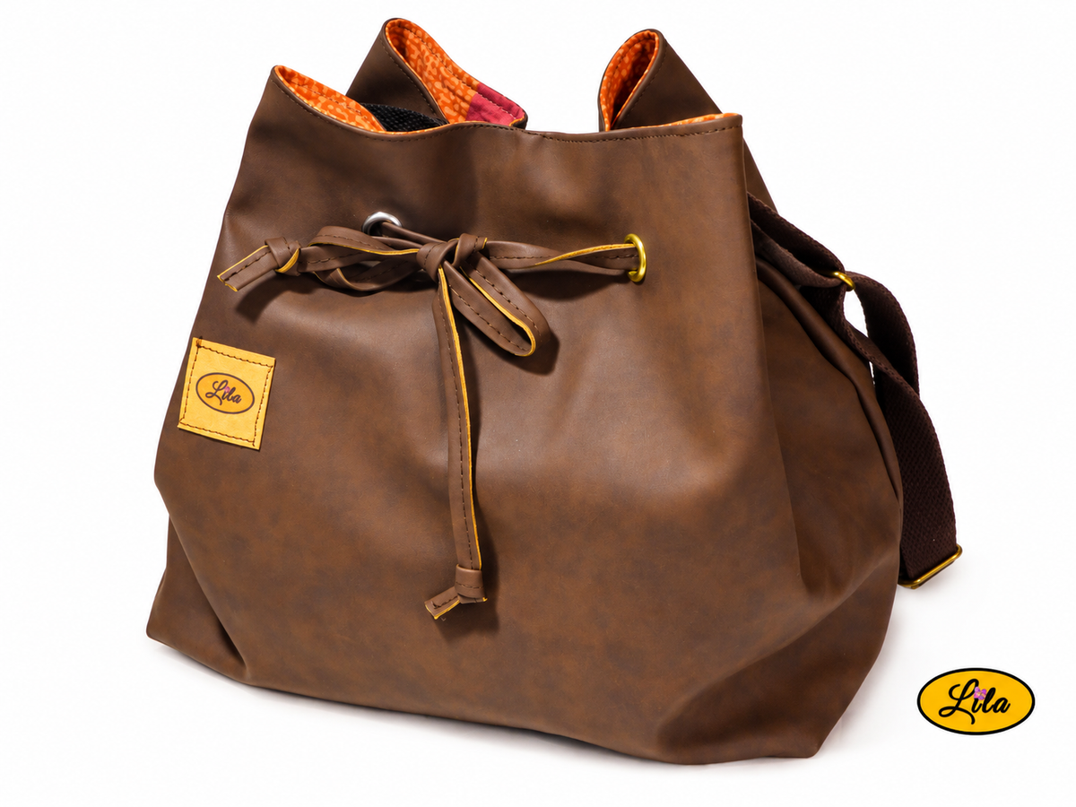Sac seau en simili cuir brun foncé légèrement de profil sur fond blanc avec lien coulissant et sangle bandoulière brune, création artisanale réalisée en matériaux recyclés
