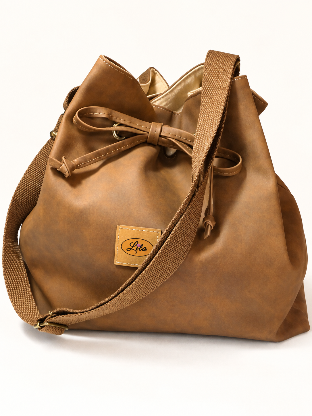 Sac seau en simili cuir brun doublé d'une ancienne tenture jaune à motifs imprimés vu de face avec sangle bandoulière brune positionnée sur le devant, lien coulissant et fermeture à pression