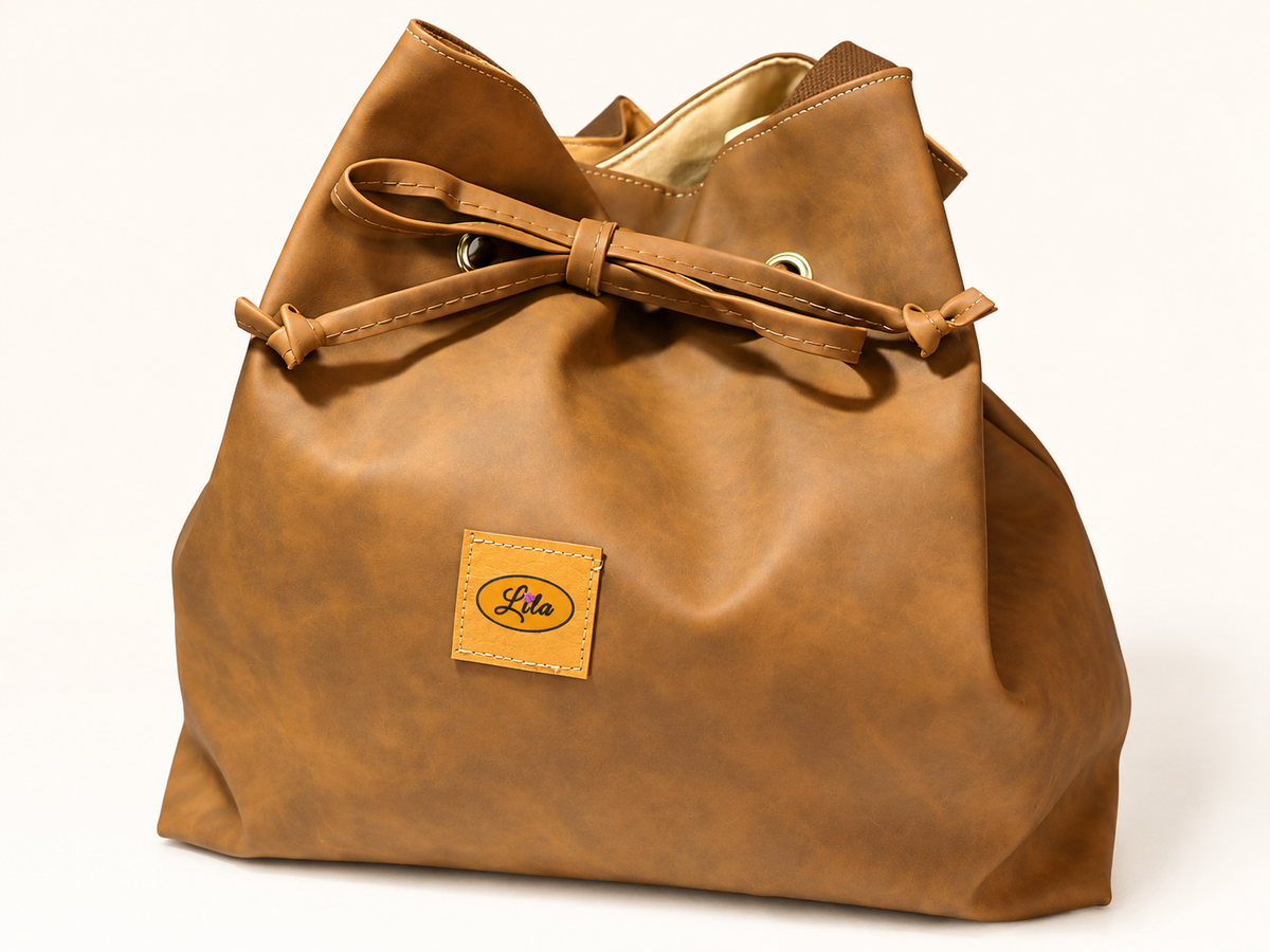 Sac seau en simili cuir brun avec doublure en ancienne tenture jaune à motifs imprimés vu de face, lien coulissant pour resserrer le sac et fermeture à pression, création artisanale