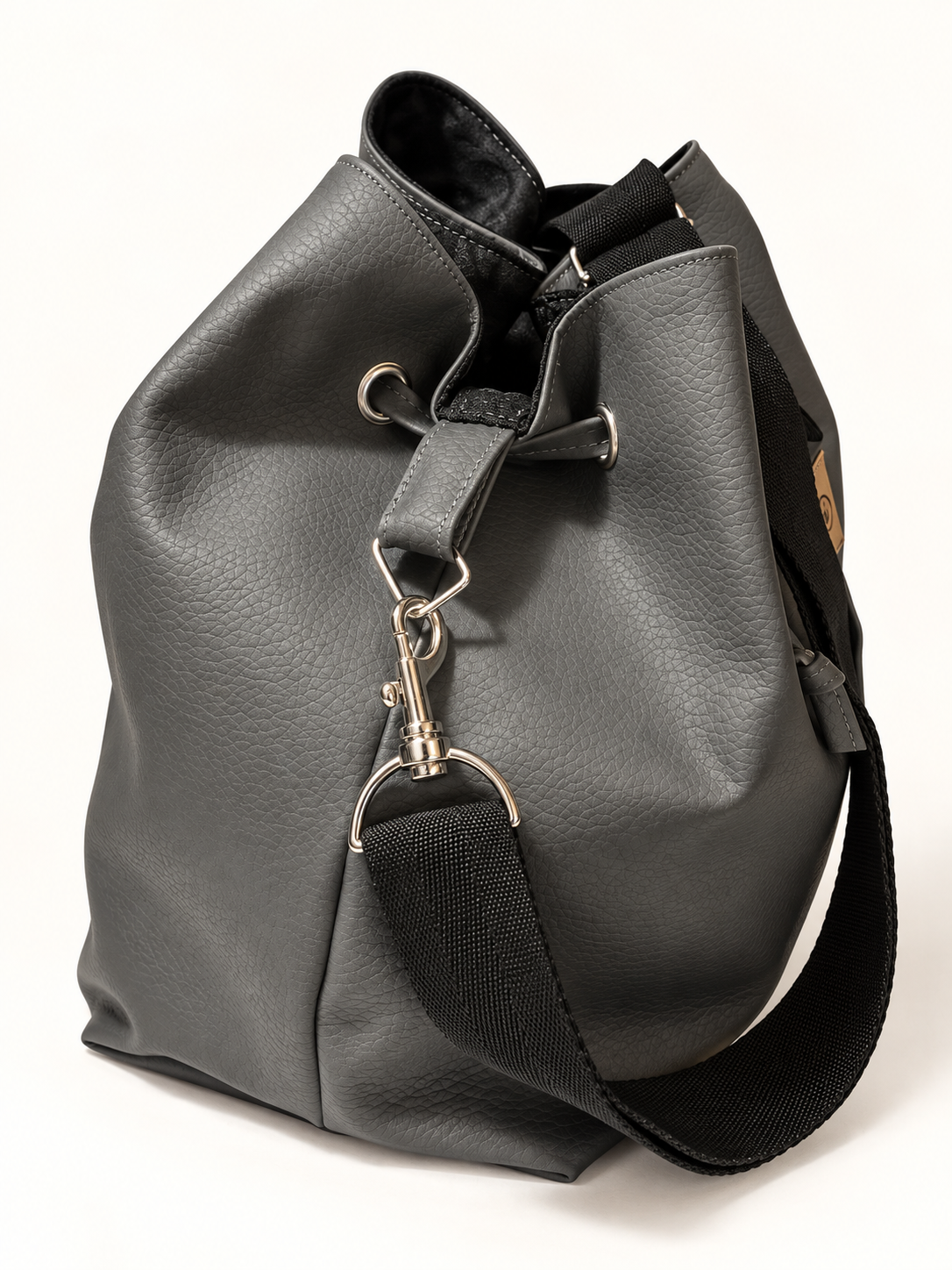 Sac seau en simili cuir gris vu de profil sur fond blanc avec sangle noire récupérée visible à l'arrière et lien coulissant, création artisanale upcyclée