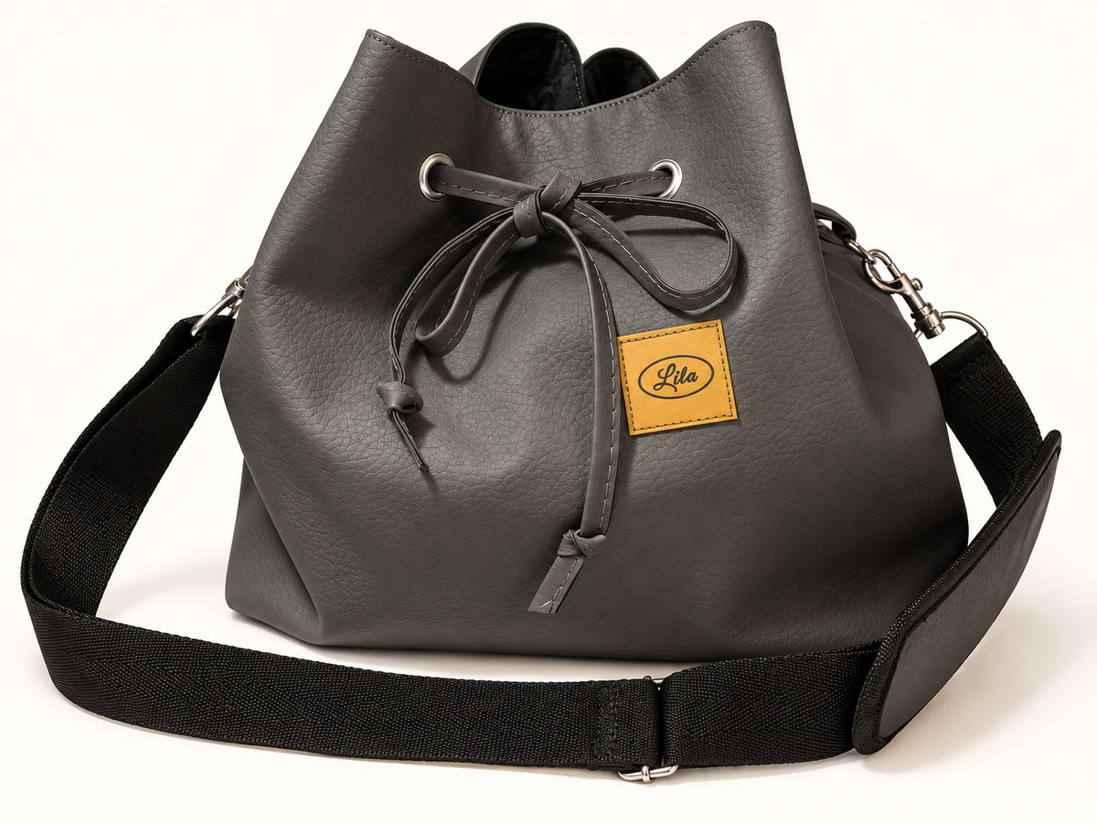 Sac seau en simili cuir gris vu de face sur fond blanc avec sangle noire récupérée au premier plan et lien coulissant, création artisanale et upcyclée