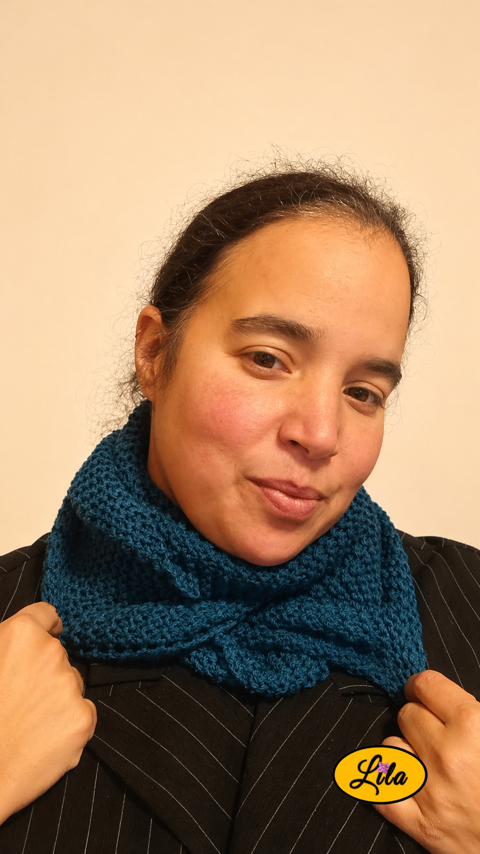 Snood en laine bleu turquoise porté profil droit avec les deux mains tenant le snood