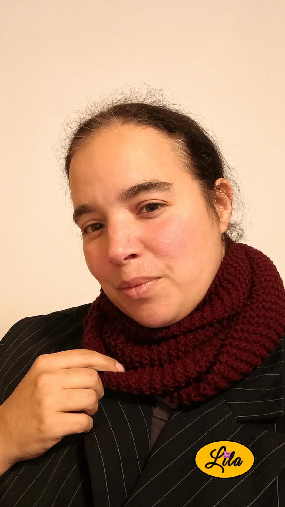 Snood en laine bordeaux foncé porté profil gauche avec une main tenant le snood