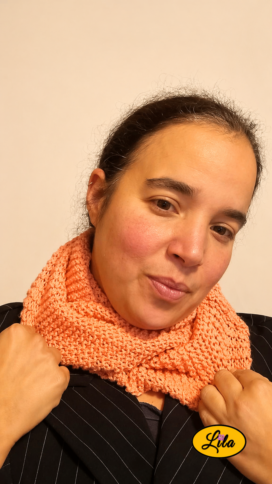 Snood en laine rose saumon porté profil droit tête inclinée avec main tenant le snood