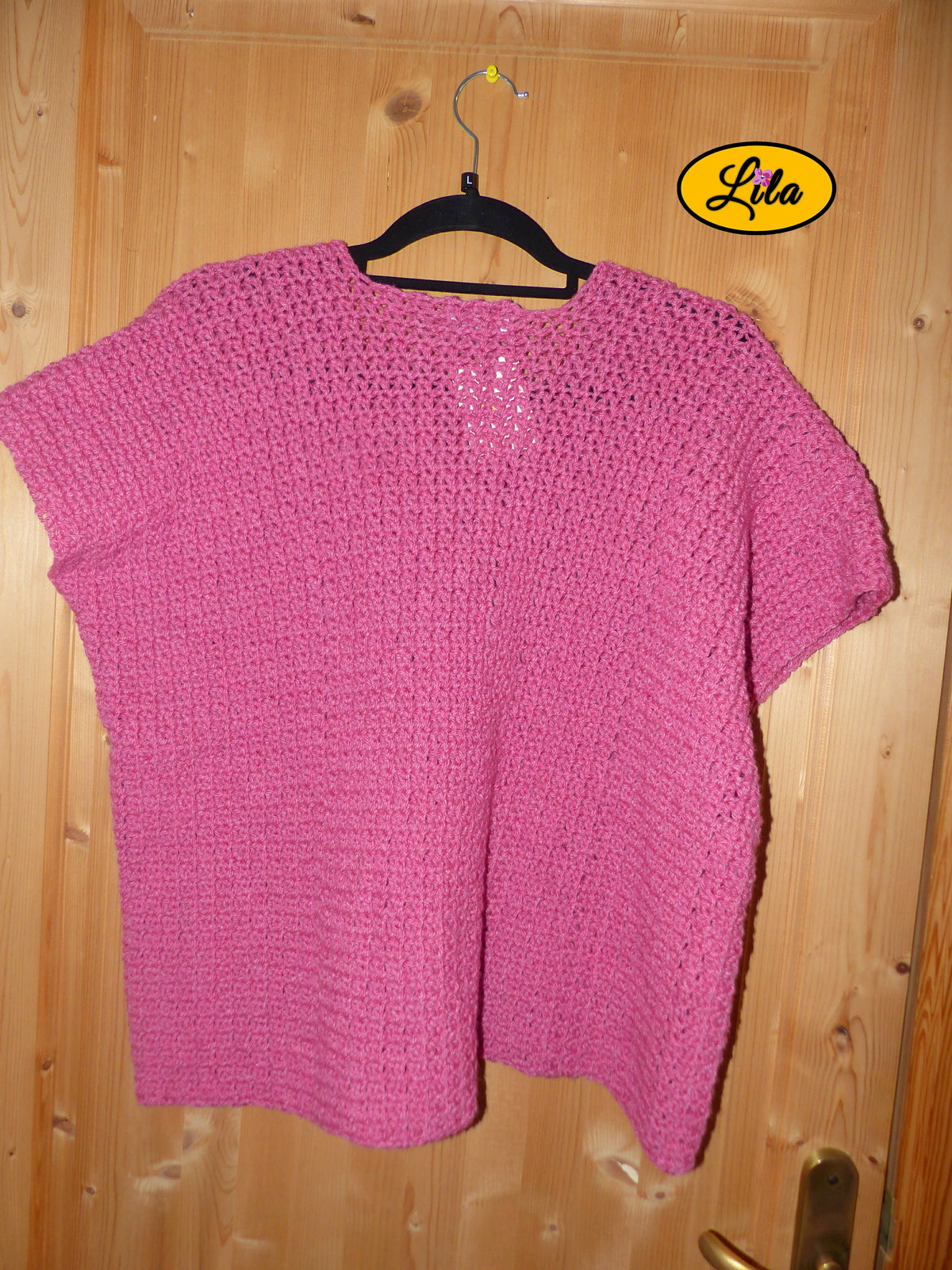 T-shirt rose crocheté à la main en laine acrylique, taille L, présenté sur cintre accroché à une porte, vue de dos