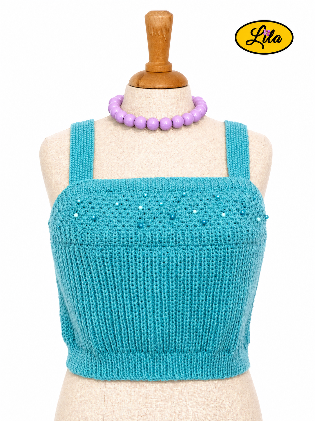 Top Augustine bleu tricoté à la main avec perles cousues porté sur mannequin de couture vue de face sur fond blanc style féminin et élégant