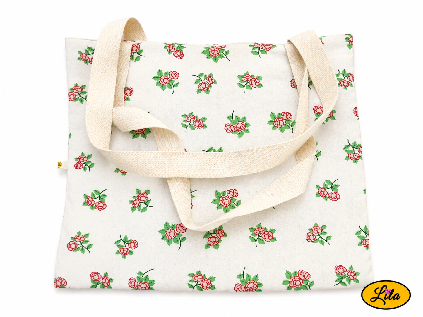 Tote bag en tissu blanc à motifs de petites fleurs roses vu de dos en vue de haut sur fond blanc avec les sangles blanc crème posées sur le sac style champêtre et artisanal