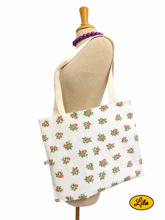 Tote bag en tissu blanc à petites fleurs roses porté sur mannequin de couture sur fond blanc avec sangles blanc crème style romantique et artisanal