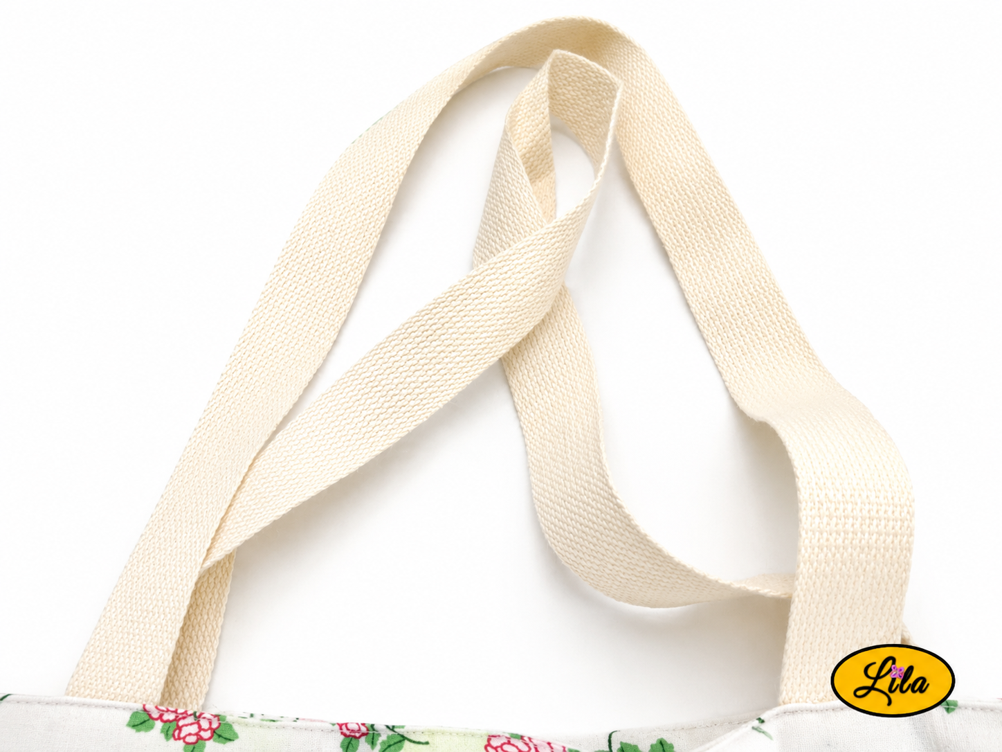 Zoom sur les sangles blanc crème d’un tote bag en tissu blanc à petites fleurs roses sur fond blanc style artisanal et soigné