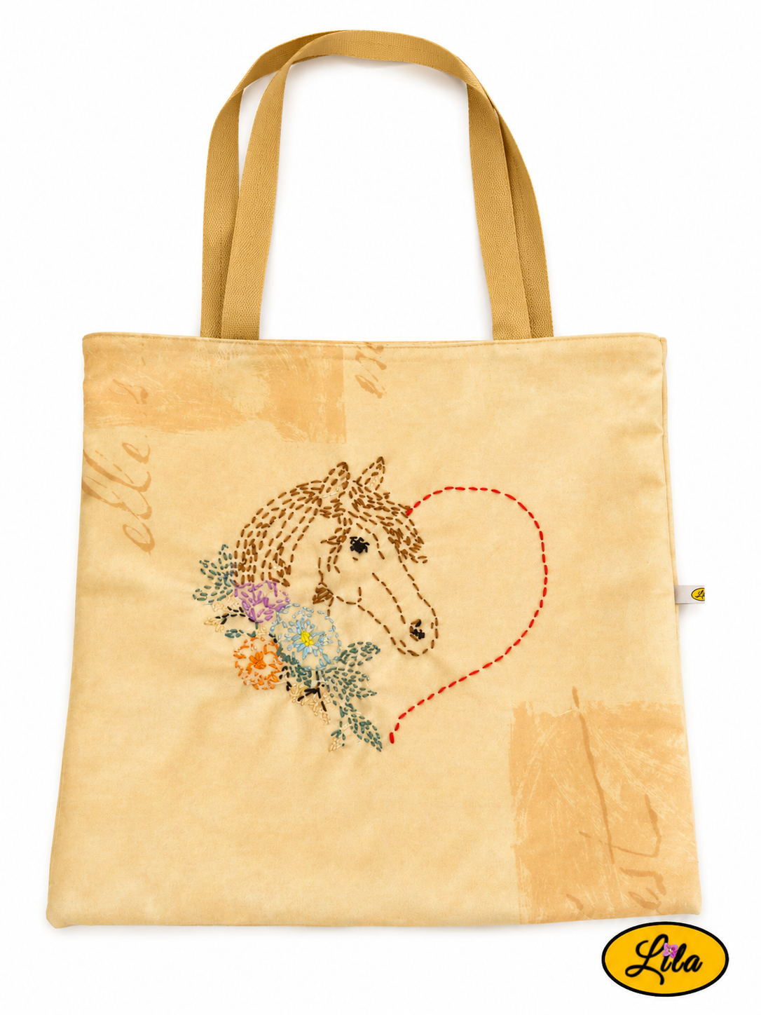Tote bag jaune vu à plat de haut sur fond blanc avec broderie artisanale représentant un cœur terminé par une tête de cheval et agrémenté de fleurs, sangles assorties visibles style romantique et artisanal