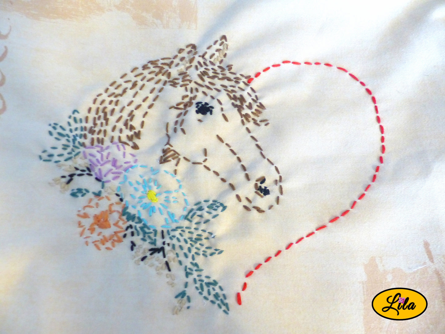Zoom sur une broderie artisanale représentant un cœur formé par une tête de cheval avec décor floral réalisée sur un tote bag jaune style équestre, romantique et fait main