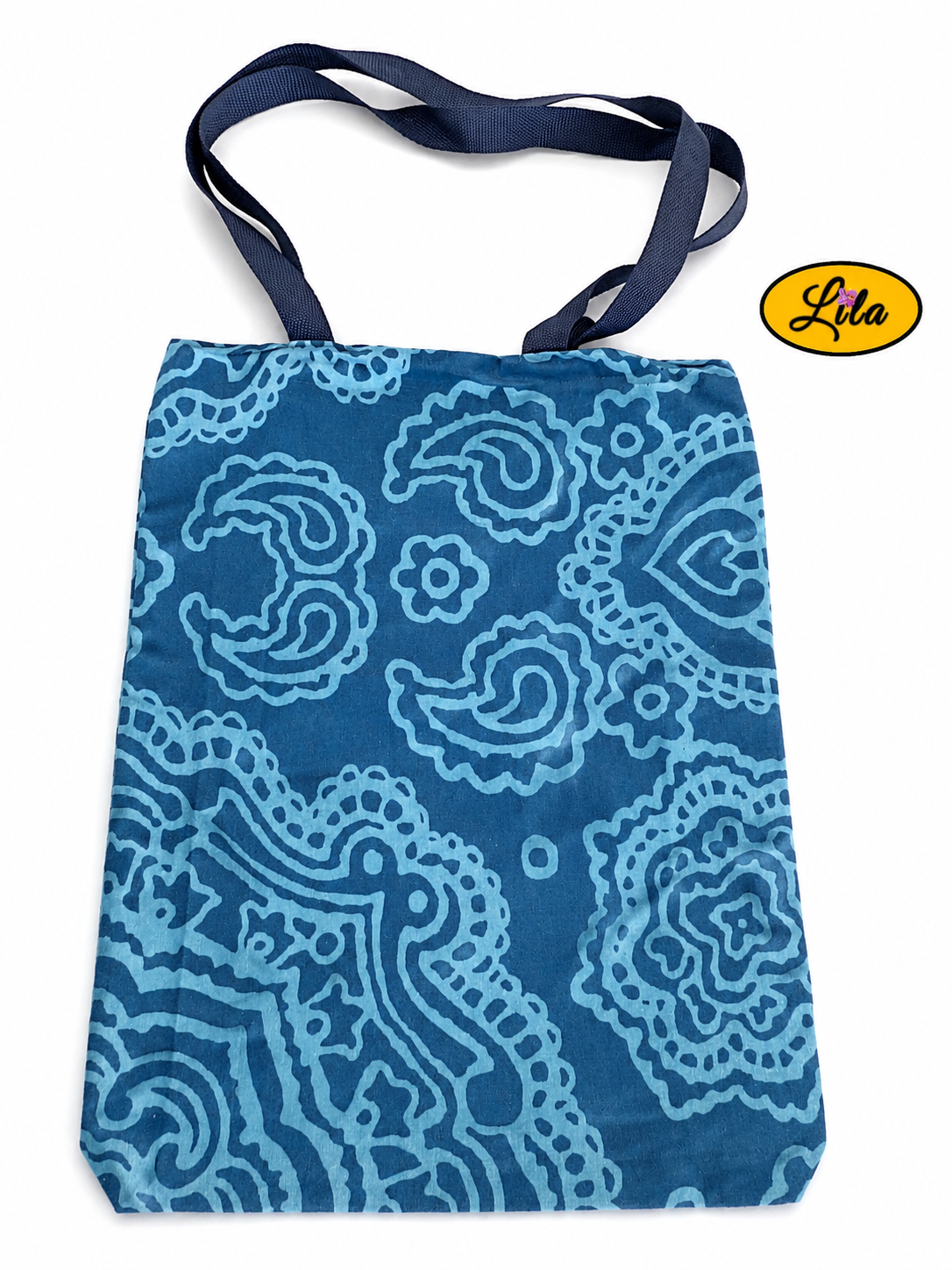 Tote bag en tissu bleu turquoise à motifs graphiques bleus vu à plat de haut sur fond blanc avec sangles placées au-dessus du sac style moderne et artisanal
