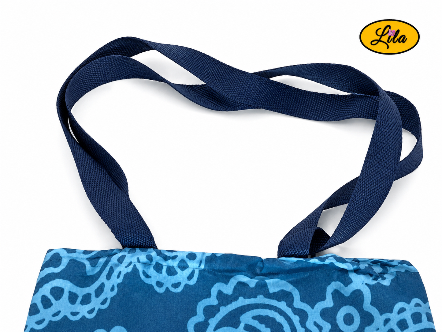 Zoom sur les sangles d’un tote bag en tissu bleu turquoise à motifs graphiques bleus sur fond blanc style artisanal et soigné