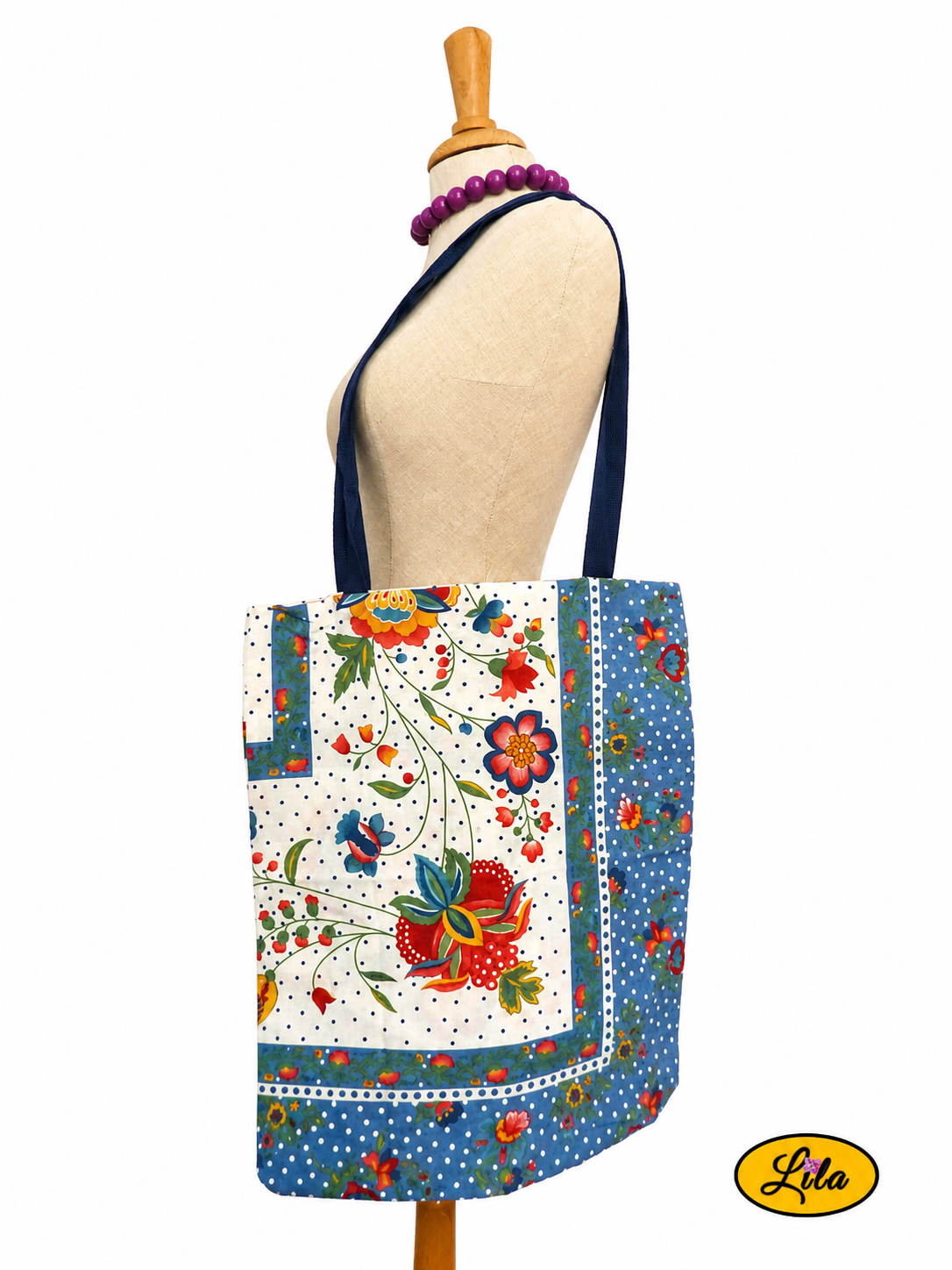 Tote bag en tissu vintage à motifs fleuris bleus porté sur mannequin de couture sur fond blanc avec sangles bleues style rétro et artisanal