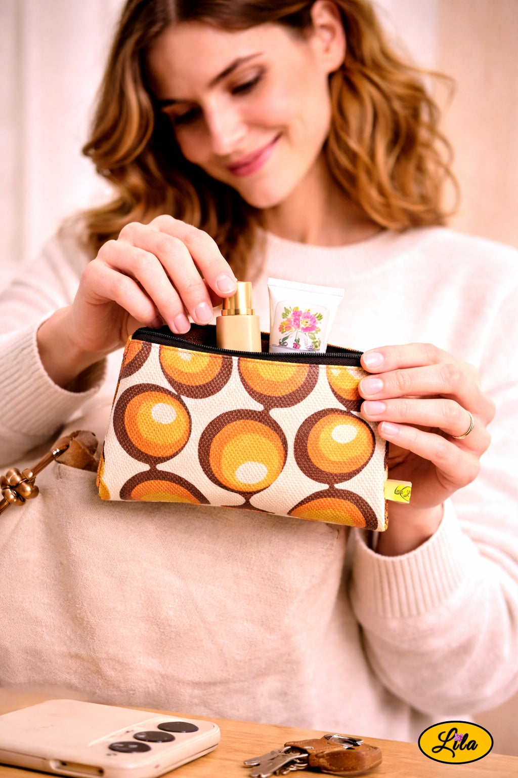 Trousse vintage aux ronds orange tenue par une jeune femme mettant la trousse en avant-plan pendant qu’elle range son maquillage style rétro et féminin